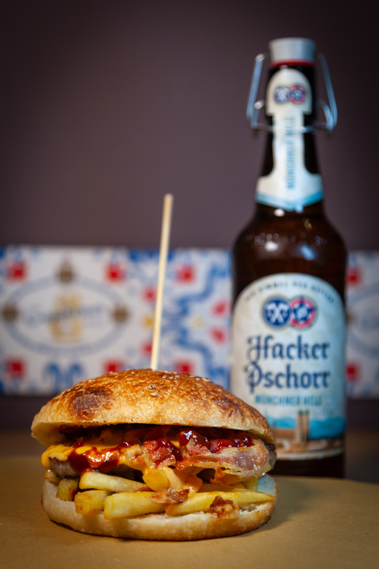 Hamburger con bacon, cheddar e patatine con birra Hacker Pschorr